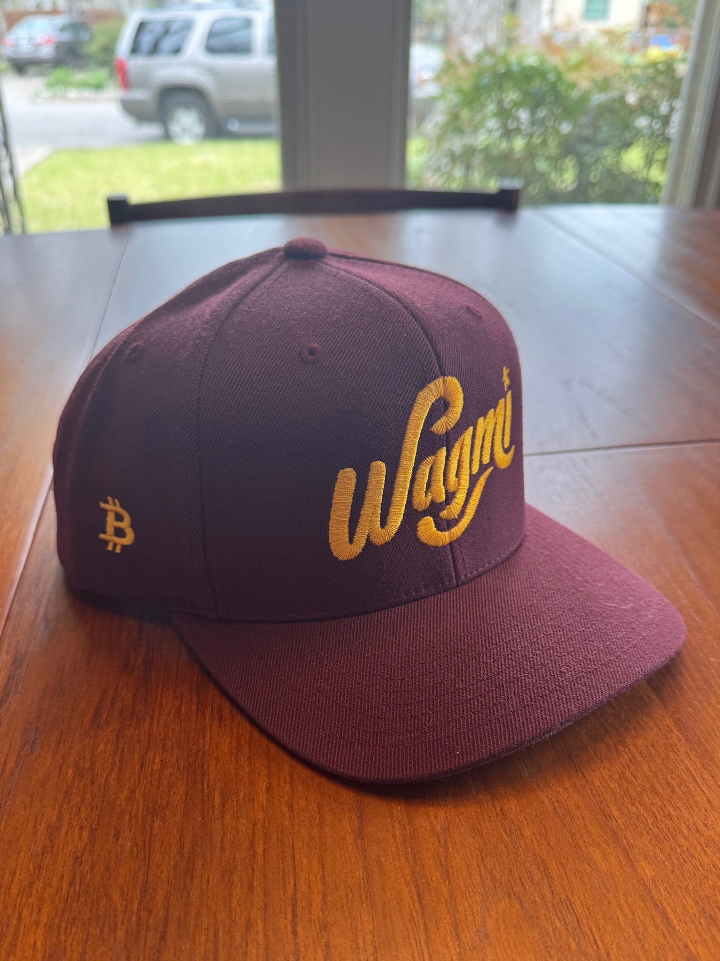 Maroon snapback hat with yellow bitcoin logo and WAGMI 'We’re All Gonna Make It' text for crypto optimism - Sovereign Goods.