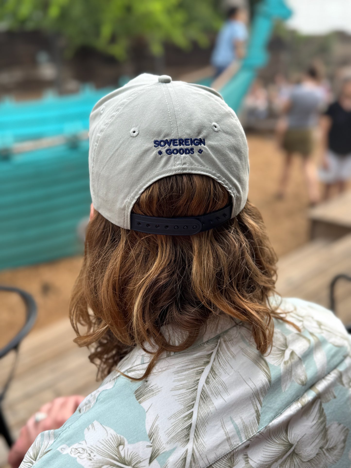 A model with long hair wears a grey golf rope cap shown from the back. Embroidered on the hat is the logo "Sovereign Goods."